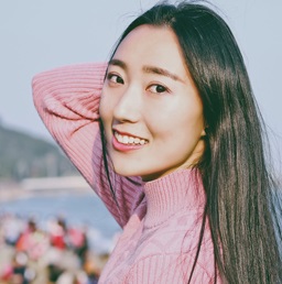 A photo of a beautiful, smiling Asian woman with the beach in the background