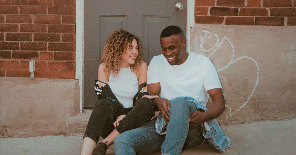 A photo of happy couple sitting outside on the pavement